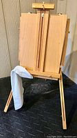 Wooden French easel shown standing with rag attached to leg, adjustable wooden panels upright