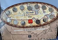 Front view of the 15 quarters in an oval display case showing their individual designs and the map background with Millennium Canada 1999 text.