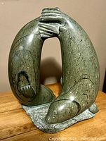 Front view of sculpture showing two seals touching heads forming an arch