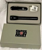 New Swiss Army set with black multi-tool and black flashlight in original box with instruction manuals.