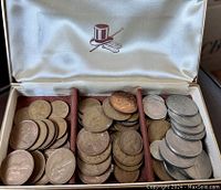 Open three-compartment lined display case holding multiple vintage British coins mainly pennies and others.