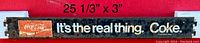 Photo of a vintage metal pushbar sign measuring 25 1/3 inches by 3 inches, featuring Coca-Cola branding and the phrase "It's the real thing. Coke."
