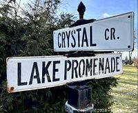 Angle view showing both enamel street nameplates mounted crosswise on the black post with finial.