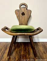 Front view of vintage wooden chair with green cushion on it.