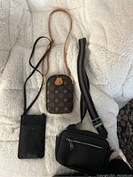 3 crossbody bags arranged on a light blanket showing front views and straps