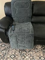 Photo showing full foldable massage mat laid open on sofa illustrating its size and plush fabric material.