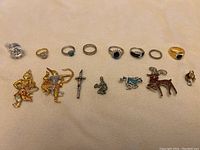 Top view of various rings and charms laid out on a beige fabric.