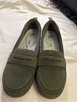 Top angle front view of the pair of Clarks Cloudsteppers olive green loafers on fabric background to show shape and color.