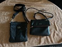 Top view of both Coach and Matt & Nat black crossbody purses on beige surface.