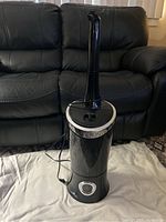 Full view of black digital humidifier with tall neck and control panel at front base.
