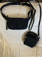 Overview of the two Lululemon bags placed on a textured cream surface, one waist bag and one crossbody bag.