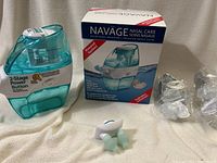 Naväge nasal irrigator device and original packaging, including mechanical unit and 2-stage power button, as well as several SaltPods in packaging.