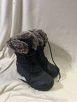 Pair of black women's winter boots with gray and brown faux fur cuff shown from the front and side, laces undone.