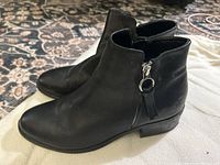 Side view showing black leather ankle booties with zipper and heel.