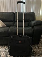 Front view of Swiss Gear black roller work bag with handle extended, showing logo and zippered compartments.