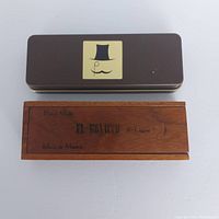 Top view of both the metal grooming kit box and wooden cigar box on a flat surface.