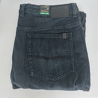 Folded dark wash denim jeans showing back pocket and belt loops.