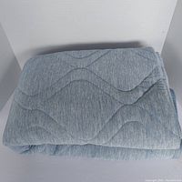 Folded light blue Brookstone Cooling Throw showing quilted wave pattern on front surface.