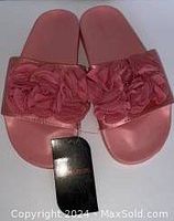 Top view of pink sandals showing the floral fabric decoration on the upper strap and attached product tag.