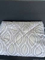 Folded king size down blanket showing overall design and color scheme with flowing curved line pattern.