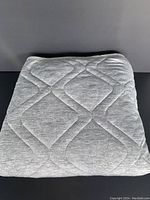 Blanket folded neatly showing front light gray quilted pattern with geometric diamond shapes.
