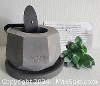 Concrete geometric fire pit showing the top with metal lid in place and caution hot embossing on side.