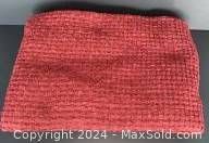 Photo showing folded red woven throw with visible texture.