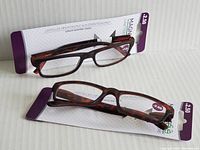 Two pairs of MAGNIFeye reading glasses in packaging showing the +2.50 magnification