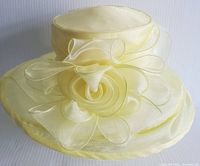 Front view showing the rosette and sheer decorative loops on yellow fabric hat.