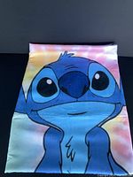 Full view of the microfiber towel with Stitch character in front, showing colorful gradient background and large facial print.