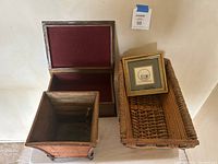 Photo showing two wooden boxes and one wicker basket with a small framed artwork on top