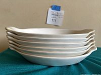 Side view of six stacked white ceramic ovenproof pots.