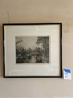 Framed black and white etching print hanging on wall, showing overall presentation and size reference.