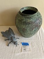 Photo showing large green patina metal vase next to a metal insect sculpture and item tag with measurements