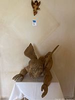 Large angel sculpture lying on a white-covered table, showing detailed wings and classical angel features.