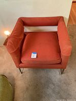 Front view of an orange Mid-Century Modern chair with visible wear on the armrest fabric. Measures approx. 25w x 25l x 25h inches.