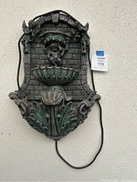 Full view of the wall-mounted outdoor garden fountain showing cherub and angels with electric cord.