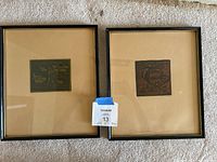 Pair of framed wall art prints side by side on carpeted floor.