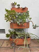 Front view of the three-tier terra-cotta planter with succulents and greenery.