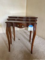 Three wooden nesting tables stacked together, showing size gradation and cabriole legs with a drawer on smallest table.