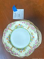 Stack of floral patterned bread plates with one plate on top showing the vibrant, multi-colored flower border and scalloped edge.