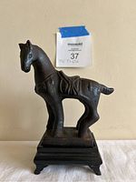 Front and side view of bronze Chinese horse statue on black wooden stand.