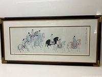 Framed lithograph showing entire scene of multiple riders on horses, traditional Chinese dress, framed in gold and brown bamboo styled frame.
