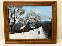 Full front view of the framed winter oil painting showing the entire scene with snow, trees, houses and two figures walking.