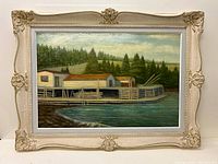Full view of the framed oil on board riverside painting showing water, dock buildings, barrels, trees, and sky.