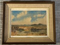 Frontal image of the framed watercolour painting depicting a landscape scene with cloudy sky, distant mountains, and foreground trees and fields.