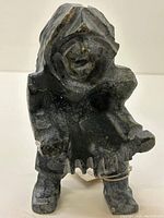 Front view of the Inuit stone carving sculpture showing figure stance and held object.