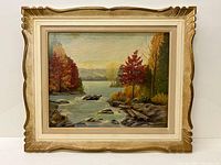 Full view of the framed oil on board painting showing a river and trees with fall foliage, signed by M. Blackwell.
