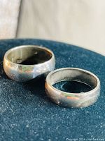 Two sterling silver banded rings side by side on blue surface, showing the rounded band profile and polished finish.