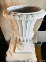 Front view of white ceramic urn planter showing detailed fluted design and rounded bead accents near base of bowl.